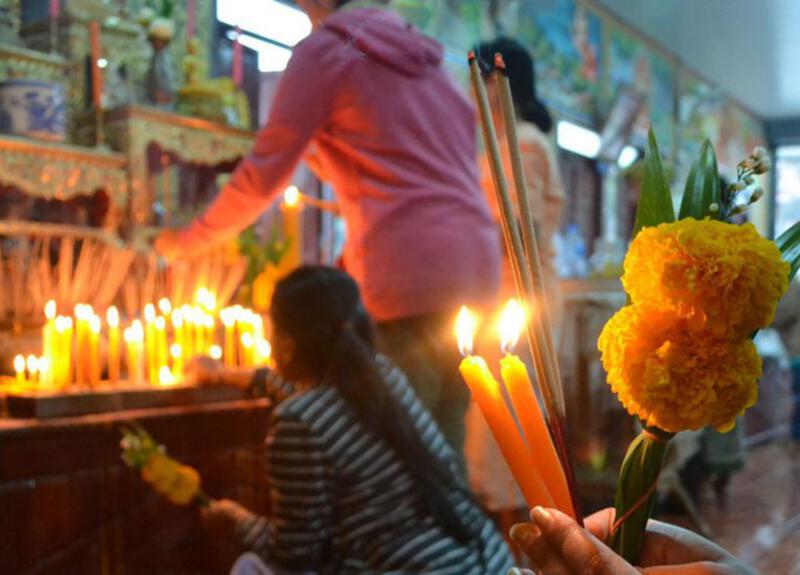 Traditional Thai Buddhist candle and flower offerings during the Buddhist Lent Day ceremony