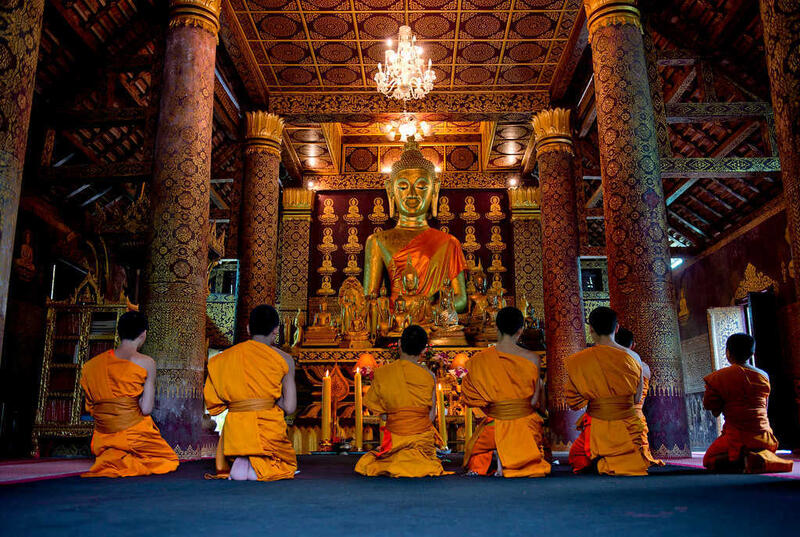 Buddhist monks meditating in a richly decorated temple during a Buddhist Lent Day ceremony in Thailand