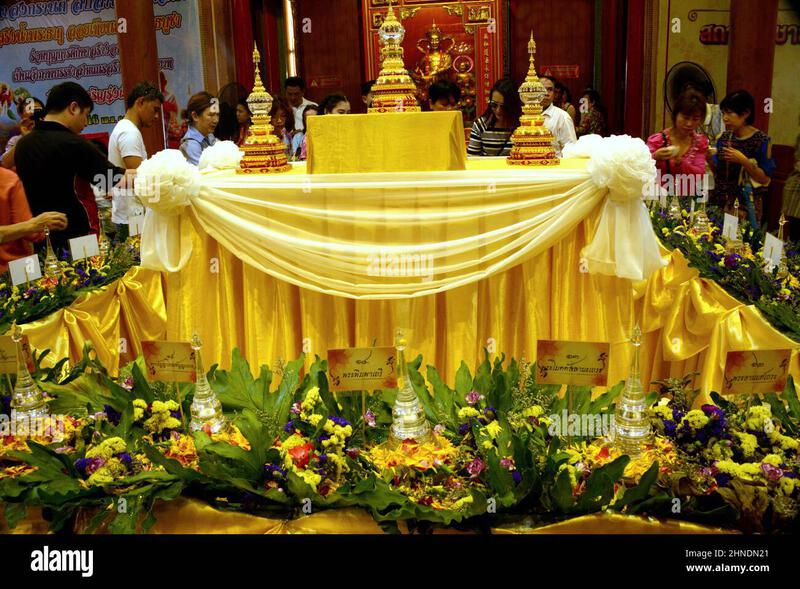 Thai Buddhist temple altar decorated with golden cloth, ceremonial objects, and flower offerings during a religious event