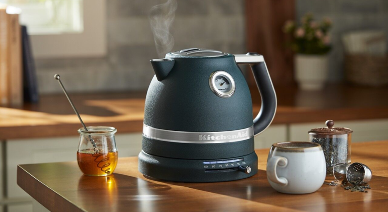 黑色 KitchenAid® 电水壶旁边是茶具和蜂蜜