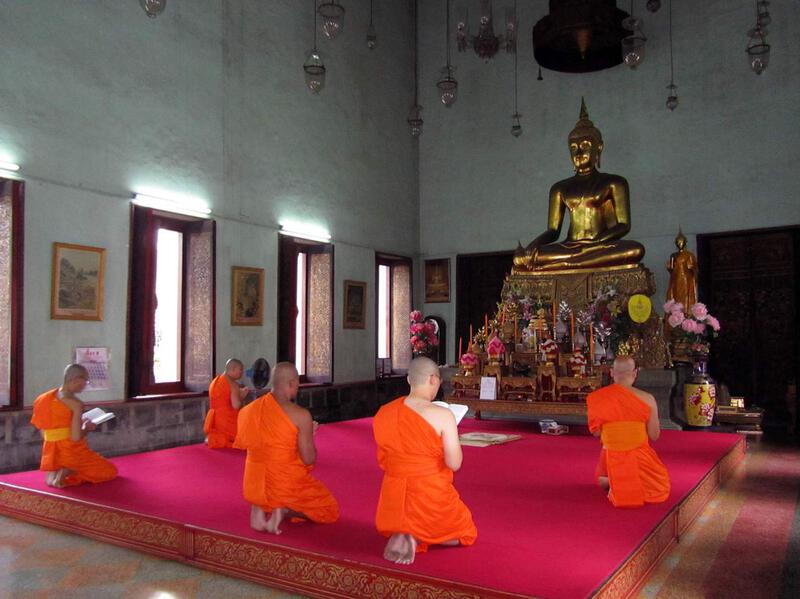Buddhist monks meditating in a Thai temple during a religious observance